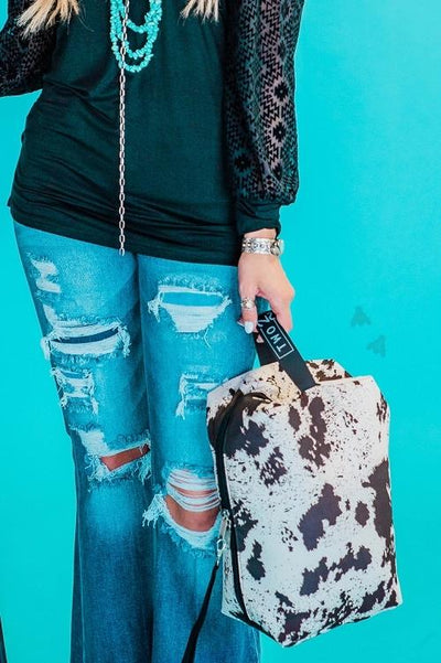 women with distressed jeans carrying cow print hide your crazy traveler by 2 fly co