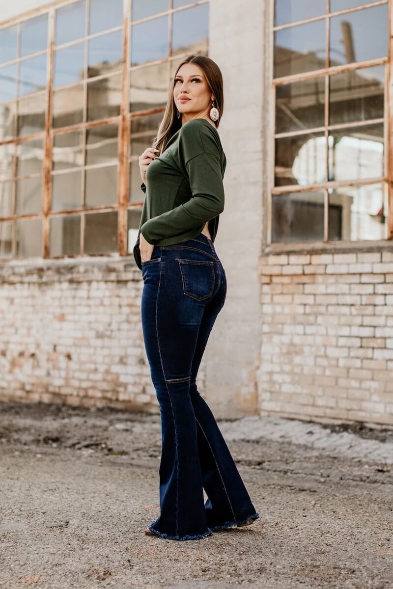 model wearing l&B flared jeans outside a brick building with large rusted windows