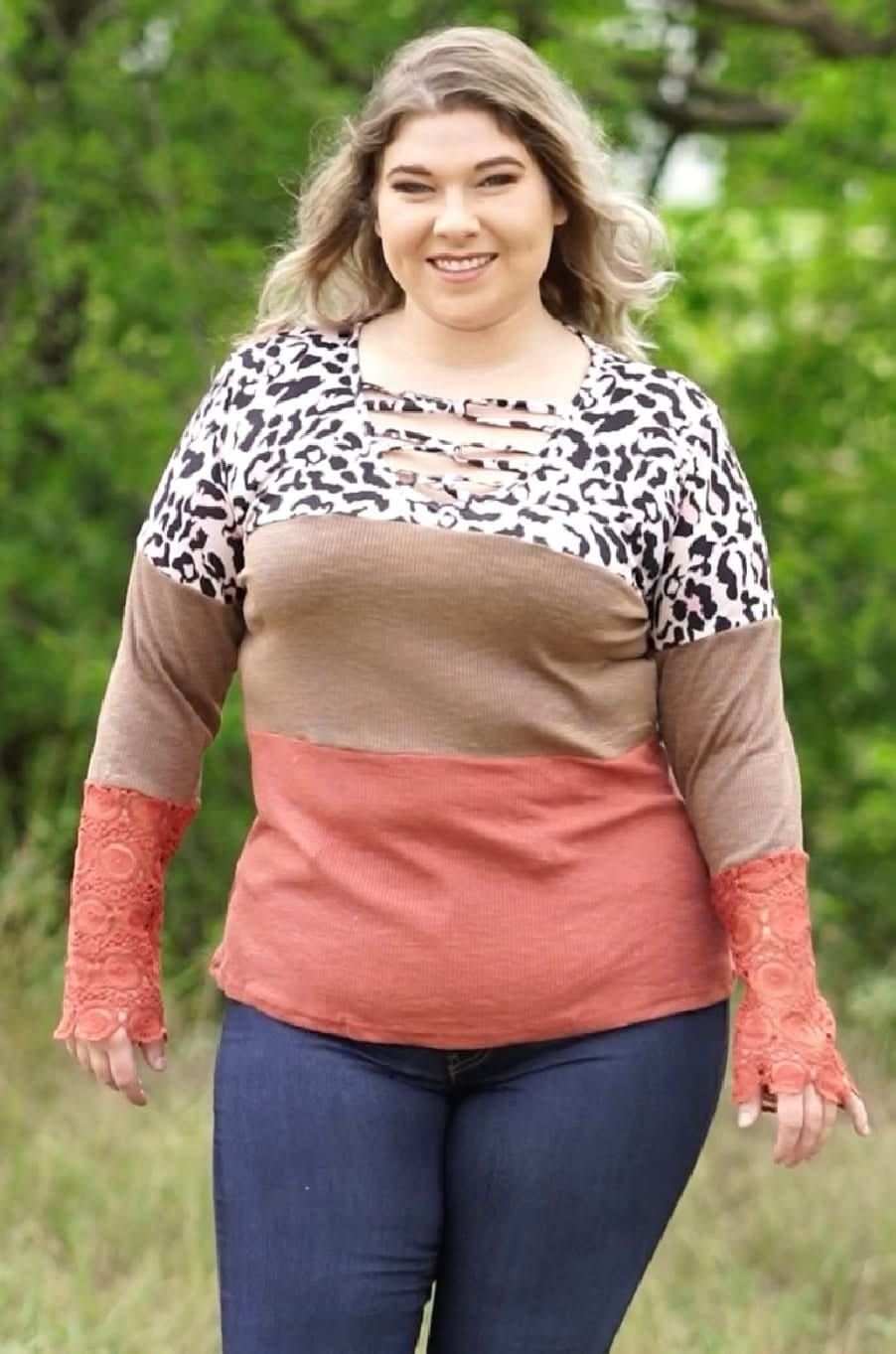 Woman wearing a colorful long-sleeve top with a leopard print pattern in an outdoor setting.
