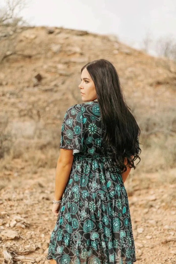  woman wearing concho printed western dress standing on rocky hillside