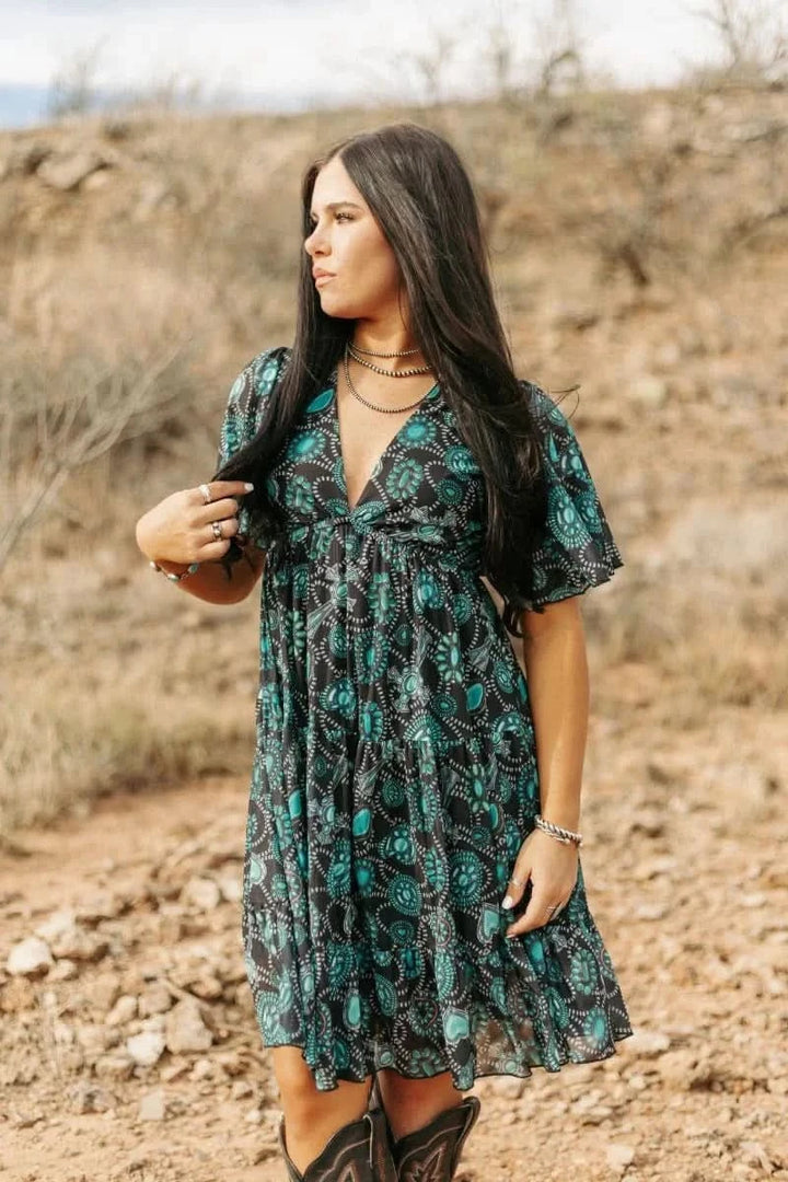  woman wearing concho printed western dress standing on rocky hillside
