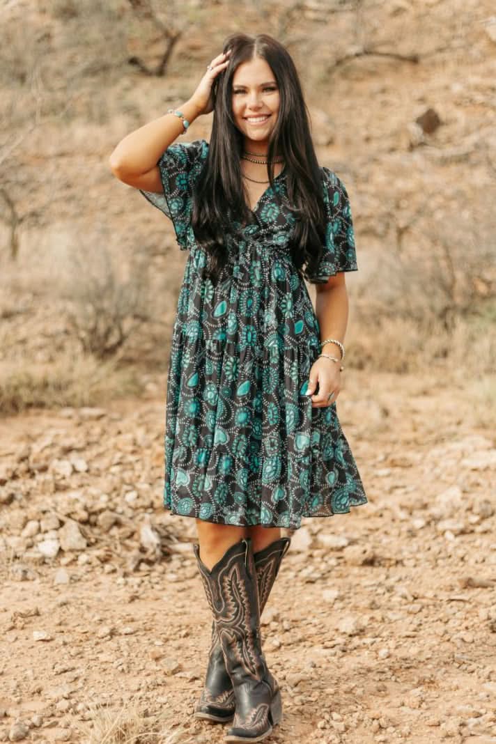  woman wearing concho printed western dress standing on rocky hillside